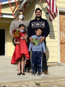 Delgado family pictured in front of their new, yellow house, still under construction.