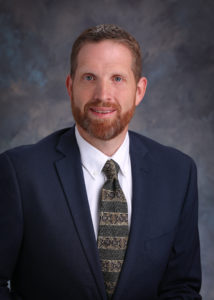 Photo of Andrew Haussler wearing a suit and tie.