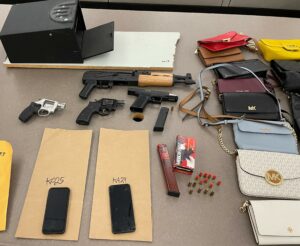 Photo of evidence collected during a search warrant including 2 stolen guns, ammo, a safe, and other property.
