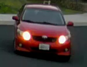 Photo of the front of a red 4-door Toyota Corolla.