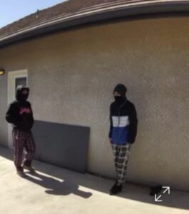 Screenshot of two suspects in fenced backyard of victim's home wearing concealing clothing.